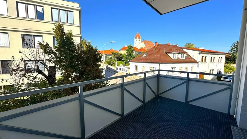 Geräumiger Balkon mit Blick auf die umliegenden Gebäude und eine Kirche in der Ferne.