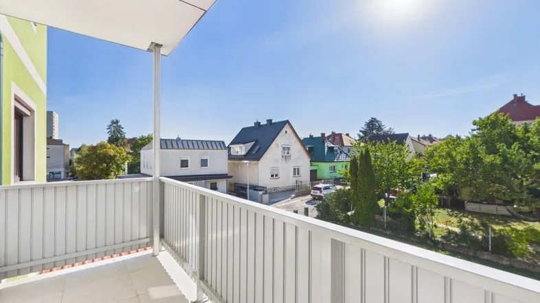 Heller Balkon mit Blick auf die umliegende Wohngegend und sonnigem Wetter.