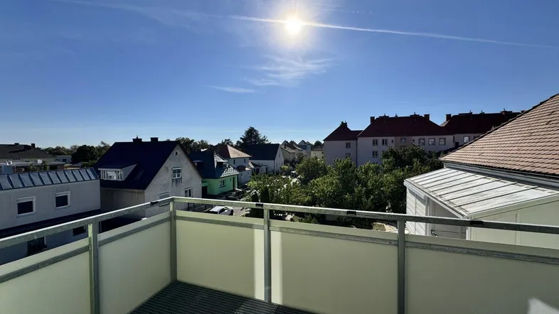 Sonniger Balkon mit Blick über die Dächer der umliegenden Häuser und viel Grün.