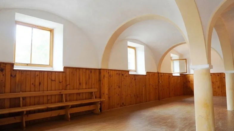 Geräumiger Innenraum mit gewölbten Decken, Holzvertäfelung und Holzbänken, ideal für Versammlungen.