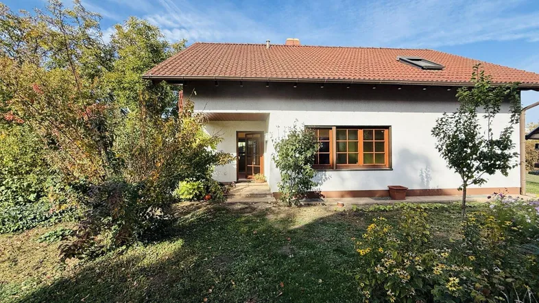 Vorderansicht eines Einfamilienhauses mit gepflegtem Vorgarten und sonnigem Himmel.