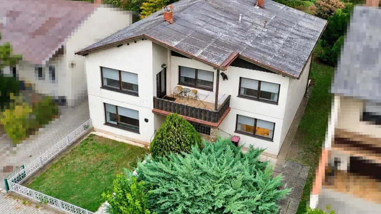 Luftaufnahme eines Einfamilienhauses mit beiger Fassade, Satteldach und kleinem Vorgartenbereich.