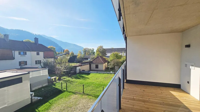 Geräumiger Balkon mit Holzboden und Glasgeländer bietet einen weiten Blick auf die umliegende Berglandschaft.