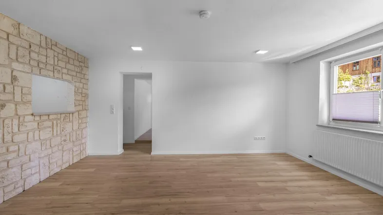 Helles Zimmer mit Laminatboden und einer dekorativen Natursteinwand, ideal als Wohnbereich.