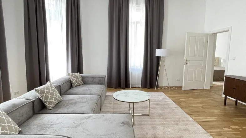 Helles Wohnzimmer mit großem Ecksofa, Holzboden und elegantem Kronleuchter.