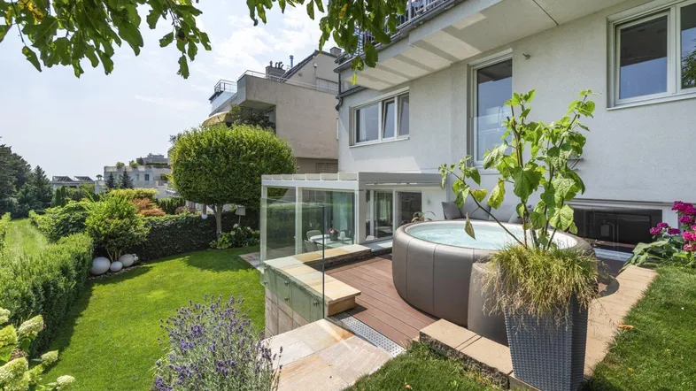 Großer Gartenbereich mit gepflegtem Rasen, Whirlpool auf der Terrasse und Blick auf die Umgebung.