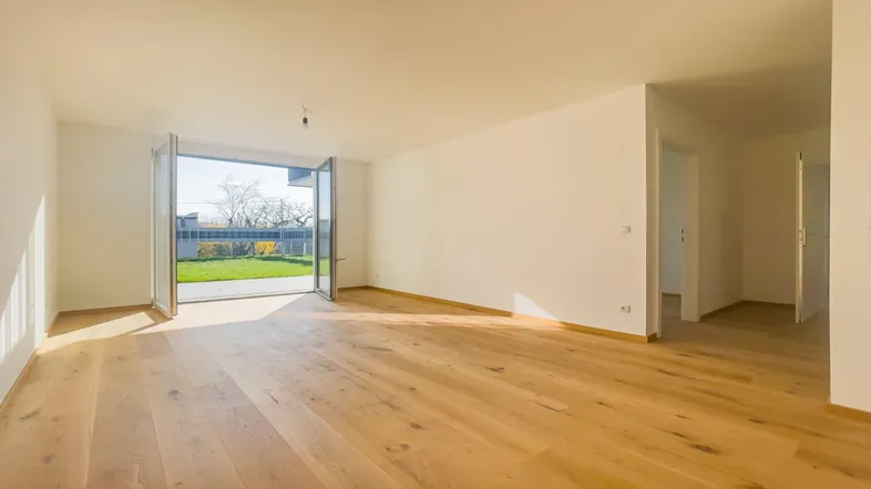 Helles Wohnzimmer mit Holzboden und Zugang zu einem kleinen Gartenbereich im Erdgeschoss.