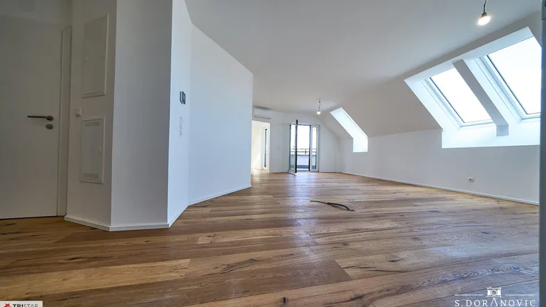 Helles, offenes Dachgeschoss mit Holzboden und Dachfenstern, ideal für Wohn- oder Essbereich.