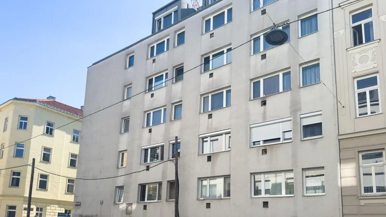 Ansicht der modernen Wohnhausfassade mit zahlreichen Fenstern und einem Kran im Hintergrund.