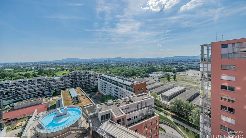 Weitläufige Stadtansicht von oben mit Blick auf Gebäude, Berge und einen Dachpool.