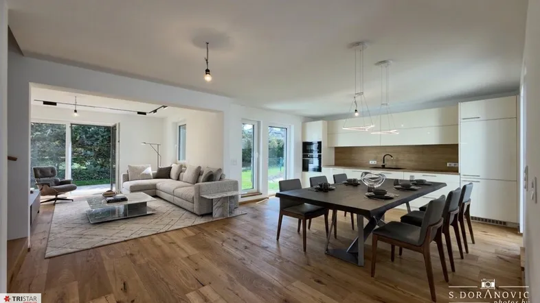 Heller, offener Wohn- und Essbereich mit moderner Küche, Holzboden und Zugang zum Garten.