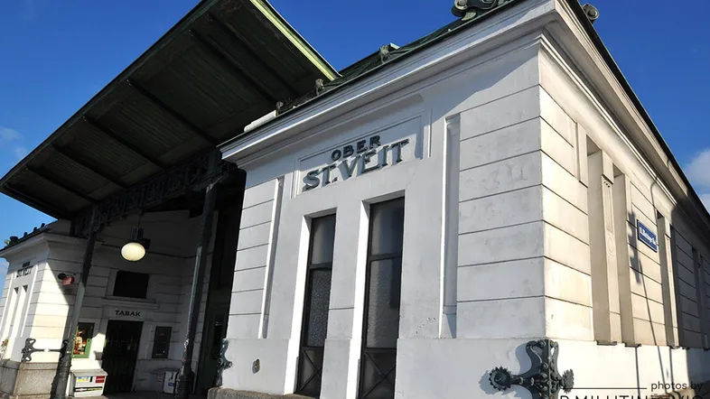 Historisches Gebäude mit markanter Architektur und dem Schriftzug "Ober St. Veit" unter blauem Himmel.