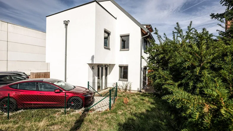 Modernes weißes Haus mit schlichter Architektur und einem gepflegten Vorgartenbereich.