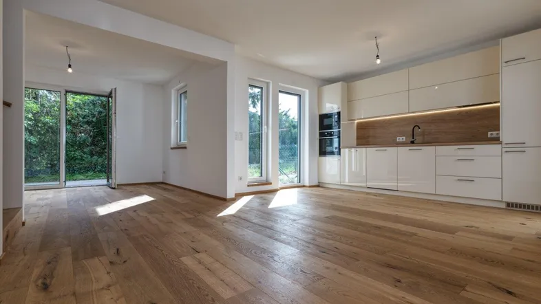 Heller, offener Wohn- und Essbereich mit moderner Einbauküche und Zugang zum Garten.