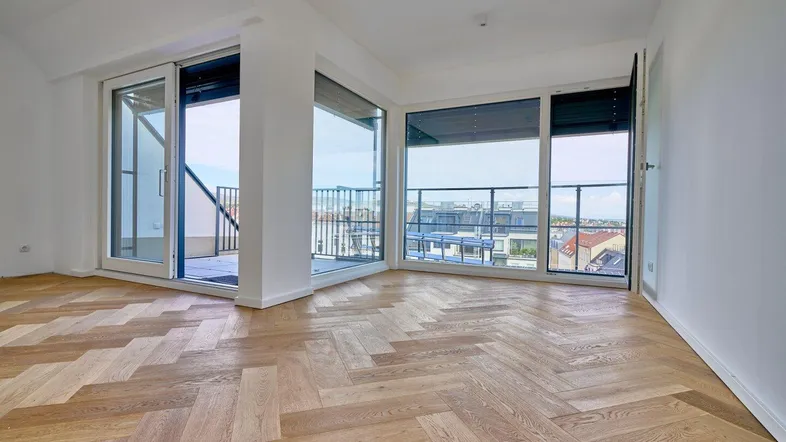 Helles Zimmer mit Fischgrätparkett und großen Schiebetüren zur Terrasse mit Stadtblick.