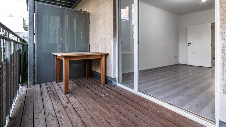 Kleiner Balkon mit Holzboden und einem Tisch, zugänglich vom Innenraum, ideal für entspannte Stunden.