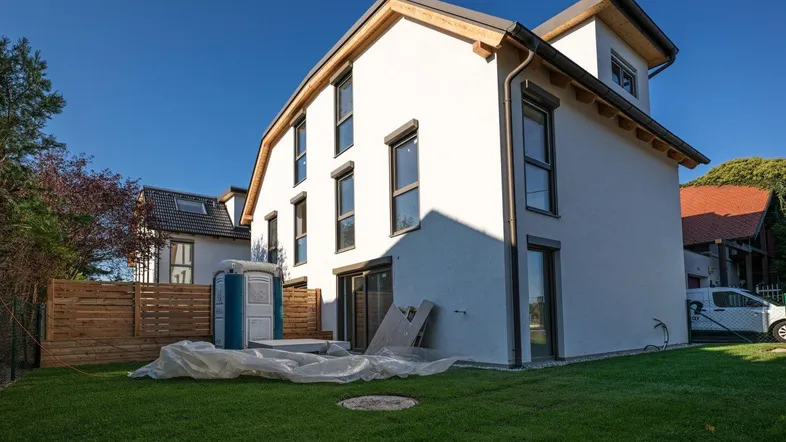Neubau eines modernen Einfamilienhauses mit weißer Fassade und frisch angelegtem Rasen.