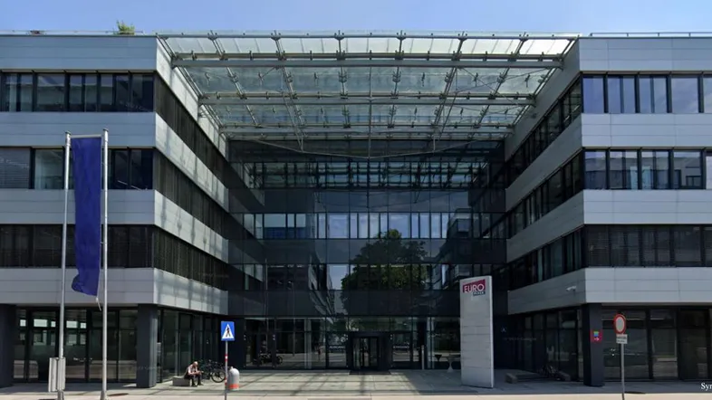 Modernes Bürogebäude mit großer Glasfassade und markantem Eingangsbereich, das eine zeitgenössische Architektur aufweist.