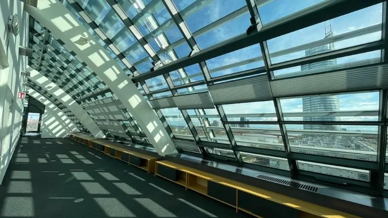 Moderner Büroraum mit geschwungener Glasfassade, die viel Tageslicht und einen weiten Stadtblick bietet.