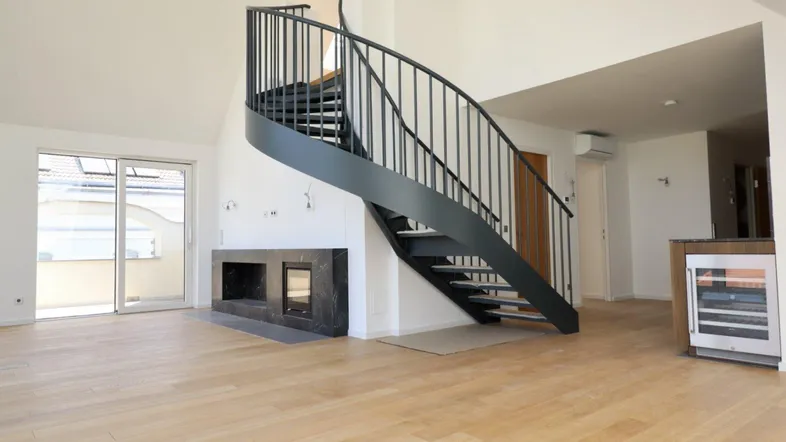 Geräumiger Wohnbereich mit eleganter Wendeltreppe, modernem Kamin und Zugang zu einer Terrasse.