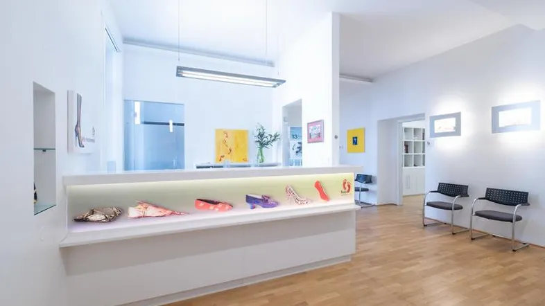 Moderne Empfangstheke mit integrierter Schuhpräsentation und Sitzgelegenheiten in einem hellen Raum.