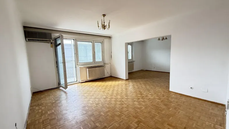 Helles Wohnzimmer mit Fischgrätparkett, weißen Wänden und Zugang zu einem Außenbereich.
