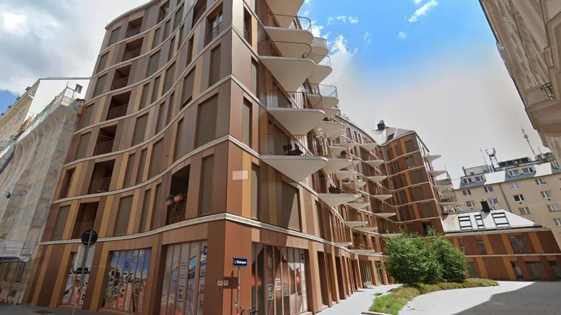 Moderne Wohngebäude-Fassade mit geschwungenen Balkonen und braunen Paneelen in der Stadt.