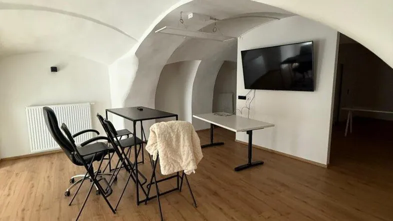 Geräumiger Büroraum mit gewölbter Decke, Holzboden und modernen Tischen, ideal für kreatives Arbeiten.