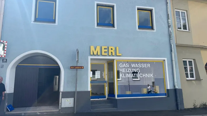Gebäudefassade eines Geschäfts mit blauer Außenwand und großen Schaufenstern, die auf Gas-, Wasser- und Heizungstechnik hinweisen.