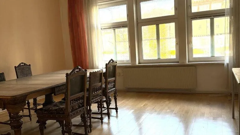 Geräumiger Essbereich mit großem Holztisch, traditionellen Stühlen und hellen Fenstern.
