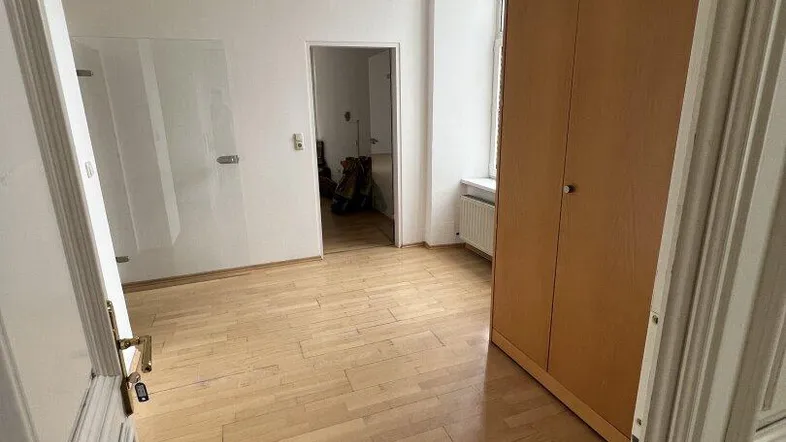 Leerer Raum mit hellem Holzfußboden, weißen Wänden und einem Kleiderschrank, bereit zur individuellen Gestaltung.