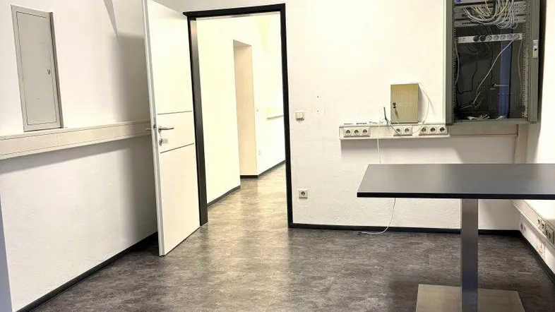Geräumiges Büro mit gewölbter Decke, modernen Böden und sichtbarer Netzwerkverkabelung an der Wand.