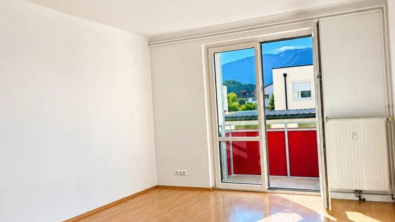 Helles Zimmer mit Laminatboden und Zugang zu einem Balkon mit Bergblick.