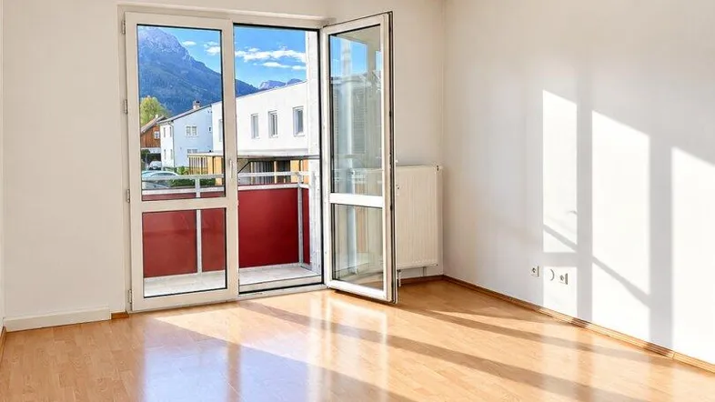 Helles Zimmer mit Laminatboden und Zugang zu einem Balkon mit Bergblick.