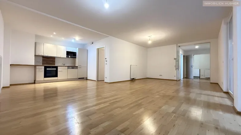 Geräumiger offener Wohn- und Essbereich mit integrierter Küche und hellem Parkettboden.