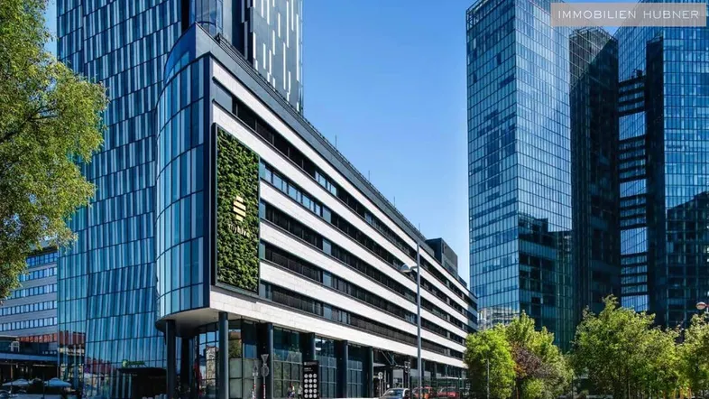 Moderne Bürogebäude mit Glasfassaden und einer begrünten Wand in einer städtischen Umgebung.