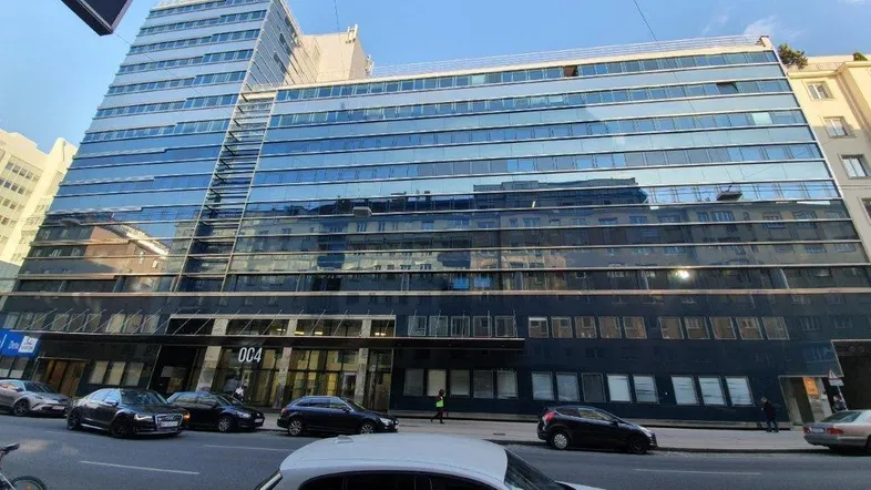 Modernes Bürogebäude mit großer Glasfassade und vielen Fenstern, gelegen an einer belebten Stadtstraße.