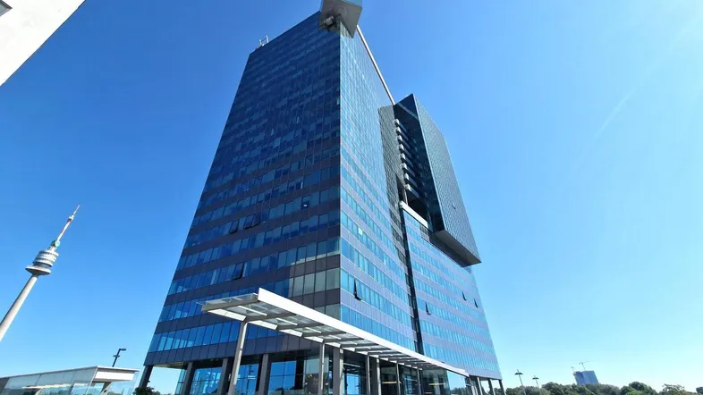 Beeindruckendes modernes Hochhaus mit Glasfassade und klarem blauen Himmel, das eine zeitgenössische Architektur zeigt.