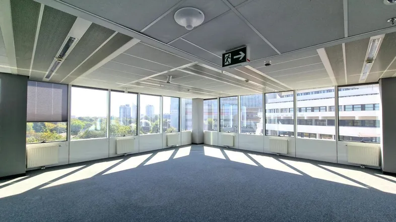 Geräumiges Büro mit Teppichboden und großen Fenstern, die viel Tageslicht und einen weiten Stadtblick bieten.