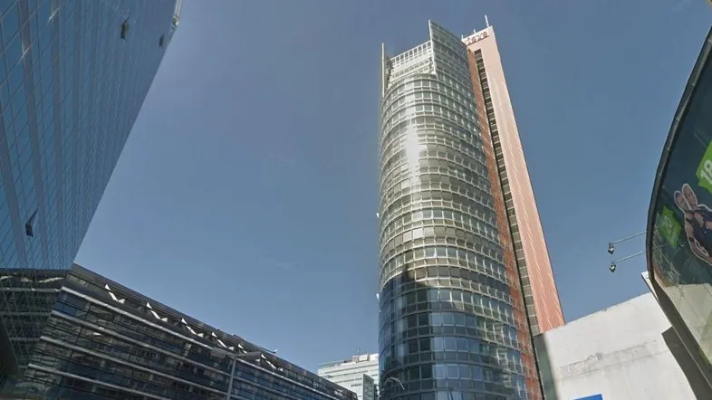 Moderne Hochhäuser mit Glasfassaden prägen die städtische Skyline und spiegeln den blauen Himmel wider.