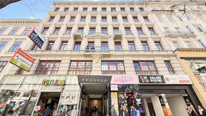 Mehrstöckiges Gebäude mit klassischer Fassade, vielen Fenstern und Geschäften im Erdgeschoss.