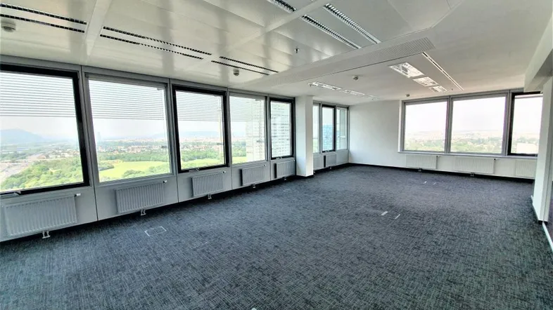 Geräumiges Großraumbüro mit Teppichboden, vielen Fenstern und weitreichendem Ausblick über die Stadt.