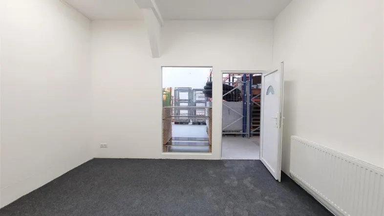 Heller Büroraum mit Teppichboden und Zugang zu einem Lagerbereich, ideal für gewerbliche Nutzung.