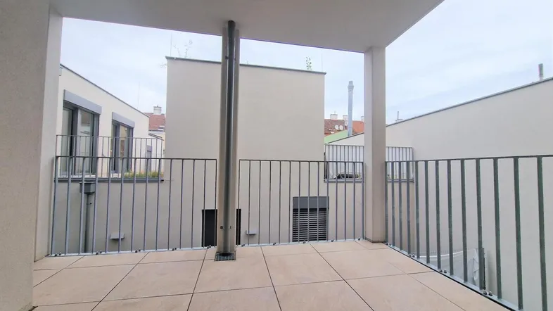 Geräumiger Balkon mit Fliesenboden und Metallgeländer, bietet einen Blick auf den ruhigen Innenhof.