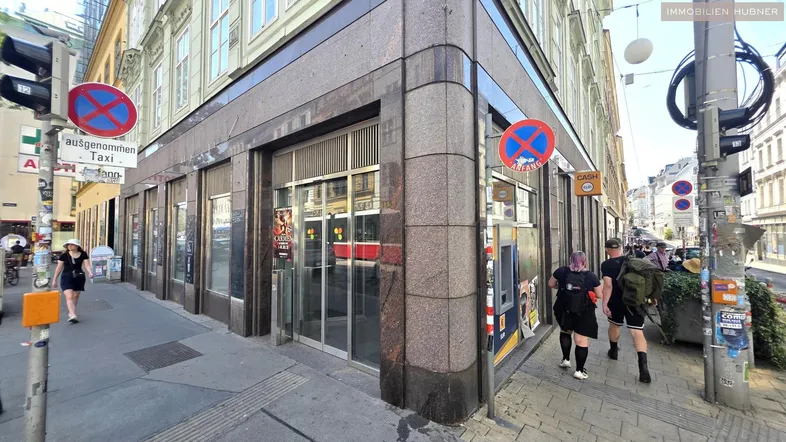 Eine belebte Straßenecke mit einem Geschäftsgebäude und Passanten in der Stadt.