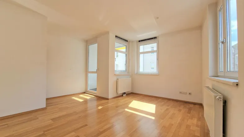 Helles Zimmer mit Parkettboden und Zugang zum Balkon, ideal als Wohn- oder Schlafzimmer.