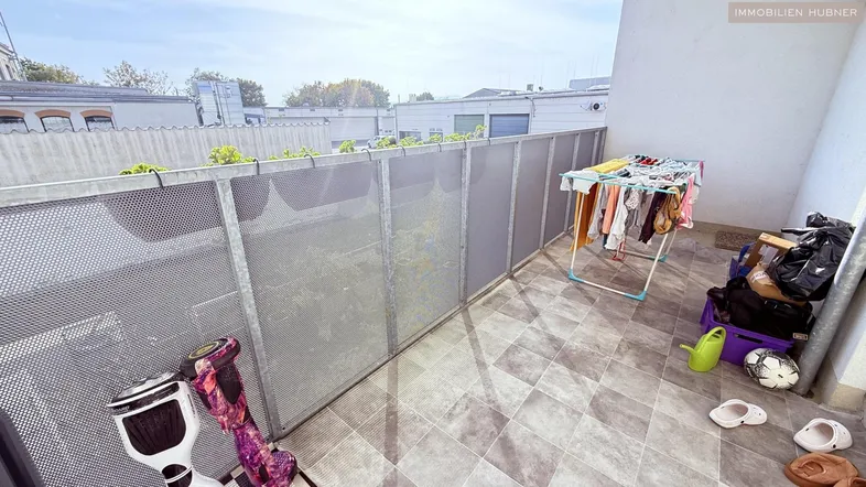 Geräumiger Balkon mit Fliesenboden und Blick auf die umliegenden Gebäude.