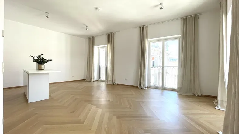 Helles Wohnzimmer mit Fischgrätparkett, hohen Decken und Zugang zu französischen Balkonen.