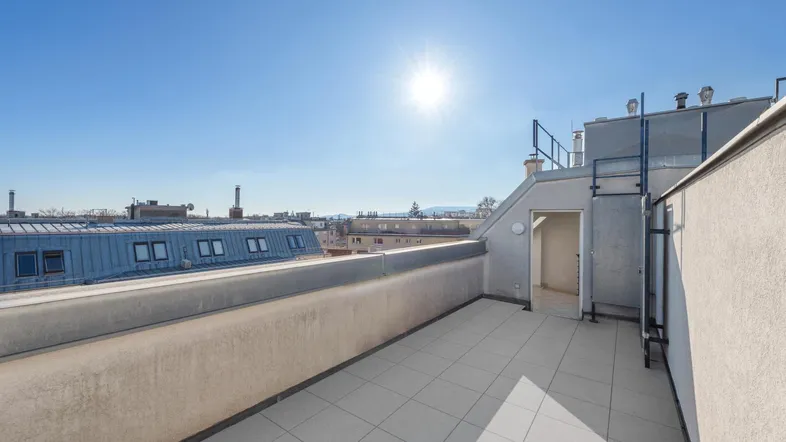 Sonnige Dachterrasse mit weitem Blick über die Stadt und umliegende Gebäude.