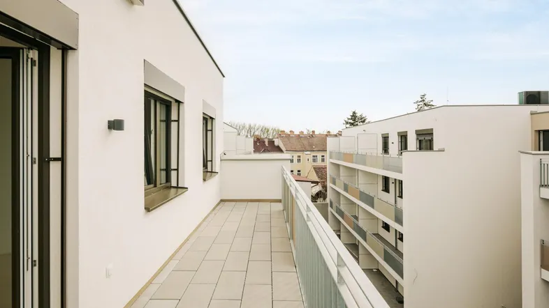 Geräumiger Balkon mit Fliesenboden und Blick auf die umliegenden Gebäude der Wohnanlage.